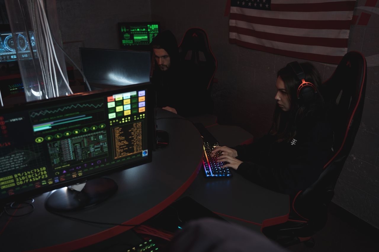 about-02 Cybersecurity professionals working on computer systems, focusing on data protection in a dimly lit room.