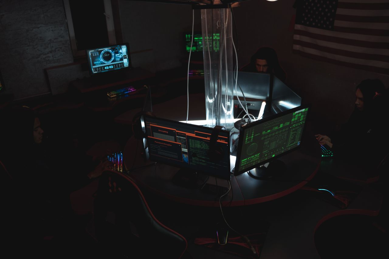 services-01 Team of cybersecurity experts collaboratively working on data protection in a dimly lit room filled with computers.
