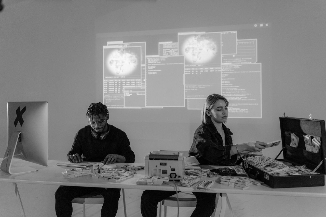 hero-02 Two professionals in a high-tech environment working with cash and computers, analyzing complex data.